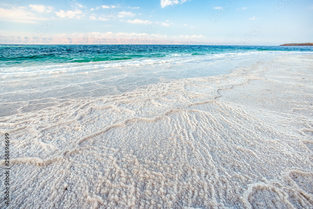 .incredibly beautiful seaside of the dead sea with blue water and white crystals of salt near.selective focus