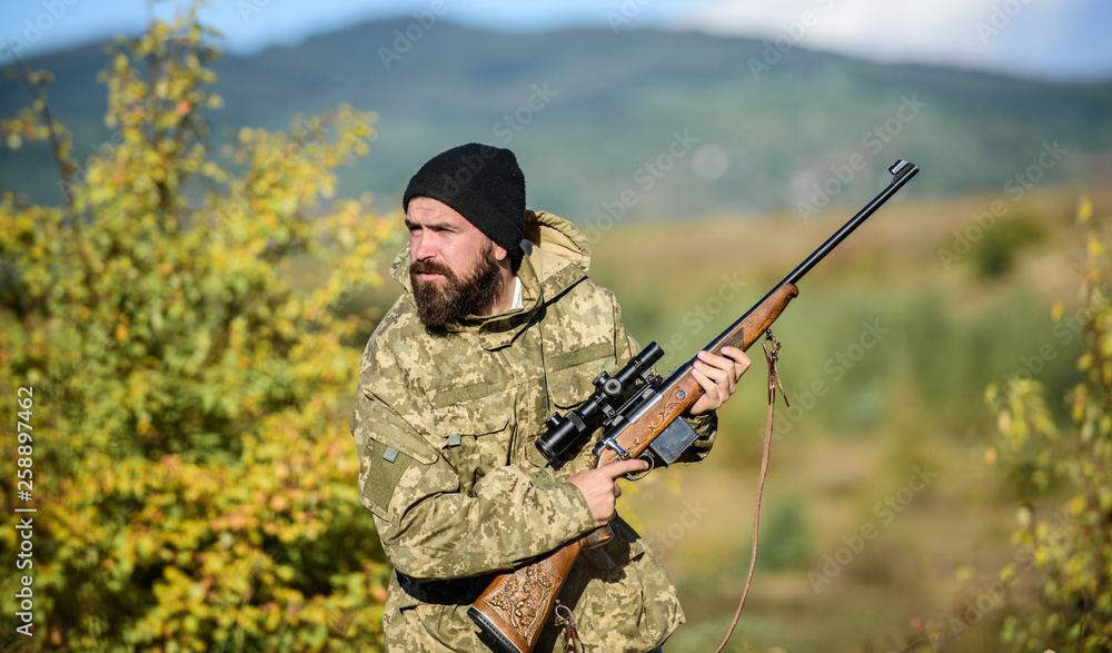 Hunter hold rifle. Bearded hunter spend leisure hunting. Focus and concentration of experienced hunter. Regulation of hunting. Hunting masculine hobby concept. Man brutal gamekeeper nature background Hunter hold rifle. Bearded hunter spend leisure hunting. Focus and concentration of experienced hunter. Regulation of hunting. Hunting masculine hobby concept. Man brutal gamekeeper nature background