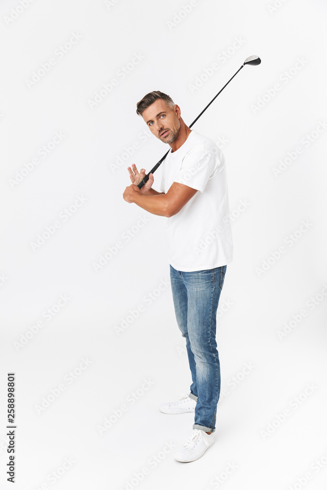 Full length image of unshaved man 30s wearing casual t-shirt holding club and playing golf Full length image of unshaved man 30s wearing casual t-shirt holding club and playing golf