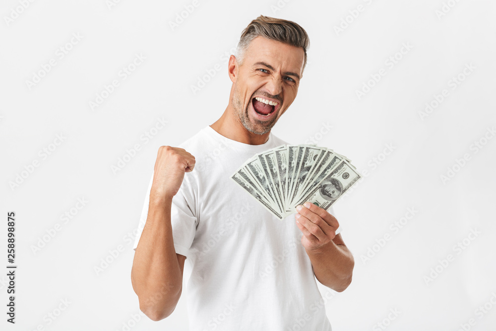 Image of masculine man 30s wearing casual t-shirt smiling and holding bunch of money banknotes Image of masculine man 30s wearing casual t-shirt smiling and holding bunch of money banknotes