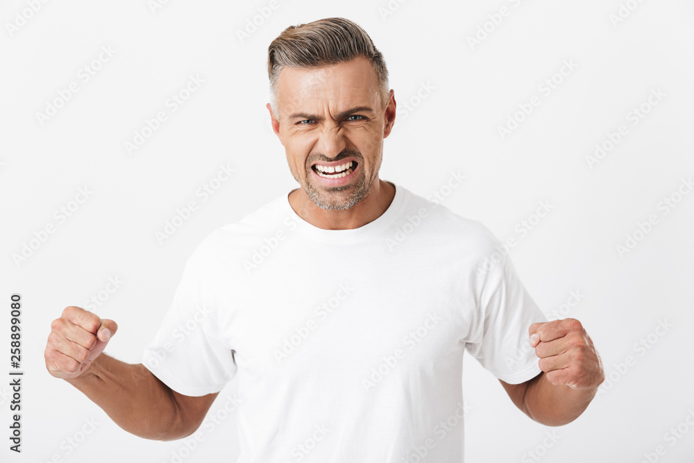 Image of muscular man 30s with bristle wearing casual t-shirt clenching fists and showing his strength on camera Image of muscular man 30s with bristle wearing casual t-shirt clenching fists and showing his strength on camera