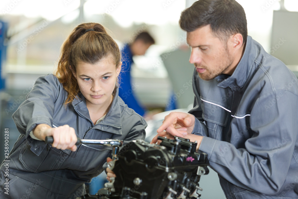 auto mechanic guiding a female trainee in garage auto mechanic guiding a female trainee in garage