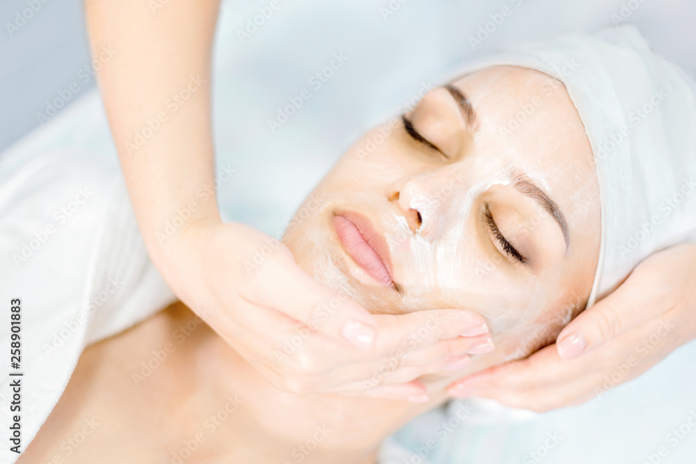 Beautician makes facial massage with mask. Beautiful young girl on spa procedure.