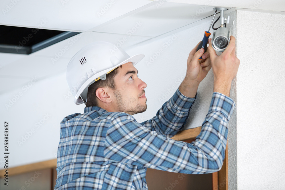 young man installing interior security camera young man installing interior security camera