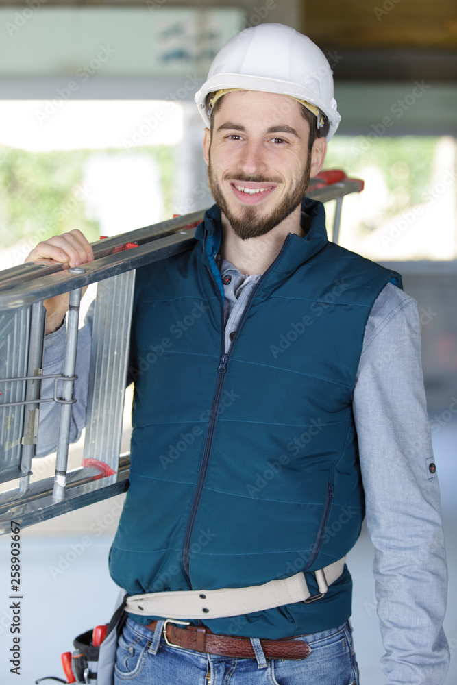 cheerful young man carrying ladder cheerful young man carrying ladder