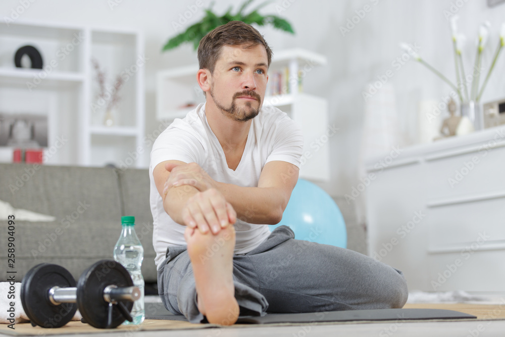 man in sportswear doing leg stretching on exercise mat man in sportswear doing leg stretching on exercise mat