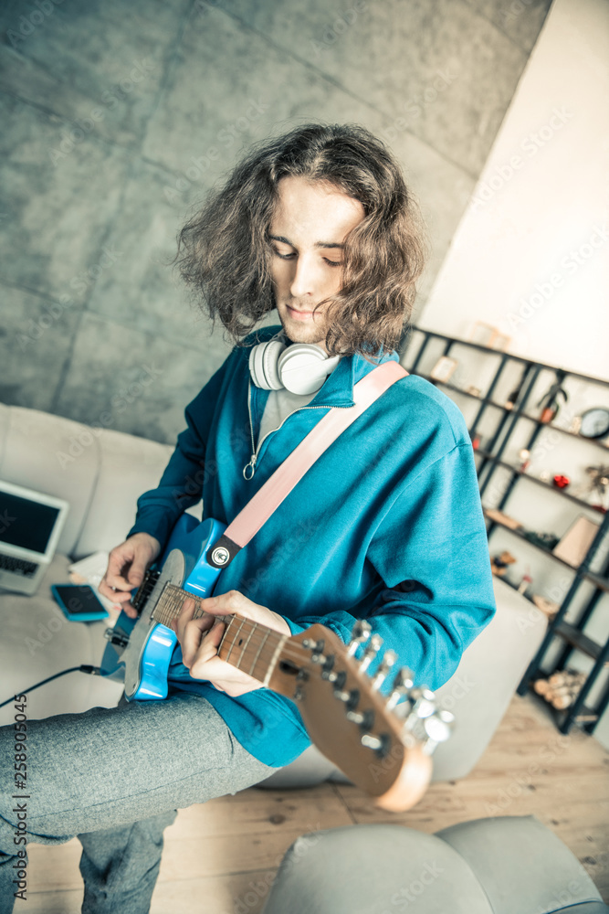Careless long-haired man being inspired while playing music
