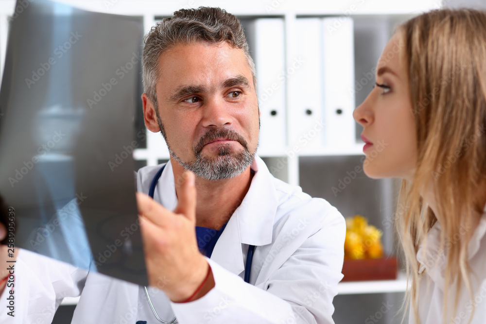 Obraz premium Mature male doctor hold in arm and look at xray photography