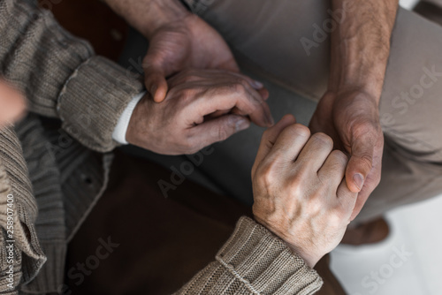cropped view of retired father and son holding hands © LIGHTFIELD STUDIOS