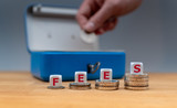 Symbol for increasing fees. Dice placed on stacks of coins form the word 
