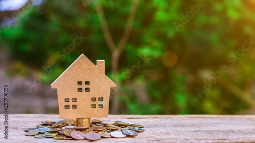 Small model of house on pile of a golden coins. - saving money for a residential and retire concepts.