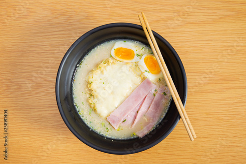 Traditional pork soup Japanese raman with boiled egg and ham in black ceramic bowl close up. photo