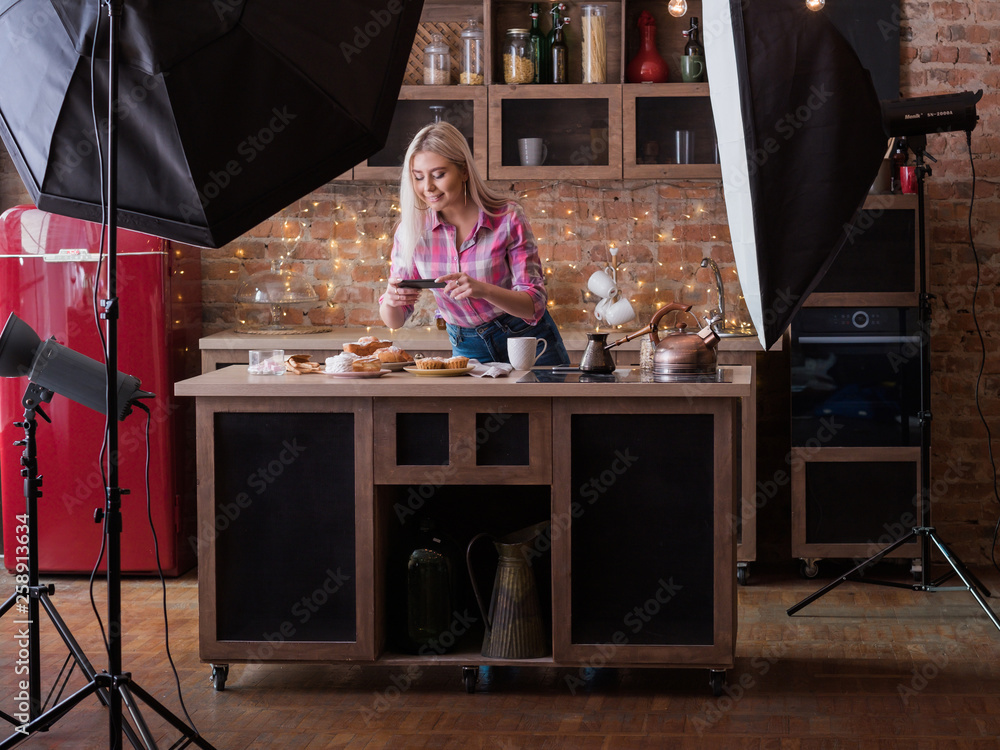 Food blogger. Backstage photography. Female lifestyle and business. Young woman with smartphone shooting pastries.
