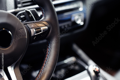 Modern car steering wheel with media control buttons, car interior details  © zorandim75