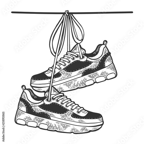 Sneakers are hanging on wire sketch engraving vector illustration. Scratch board style imitation. Black and white hand drawn image.