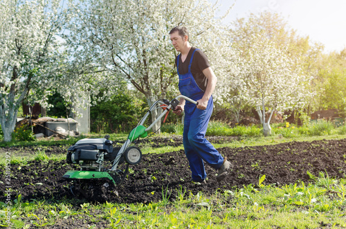 Man working in the spring garden with tiller machine