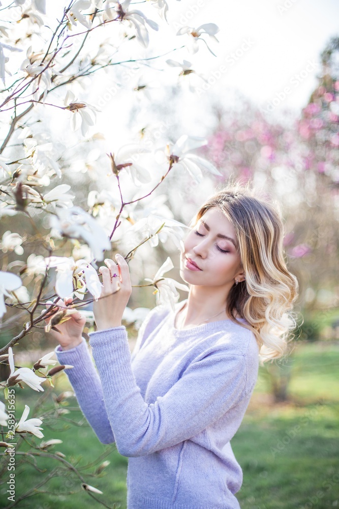 Spring portrait of beautiful young blonde woman near magnolia Spring portrait of beautiful young blonde woman near magnolia