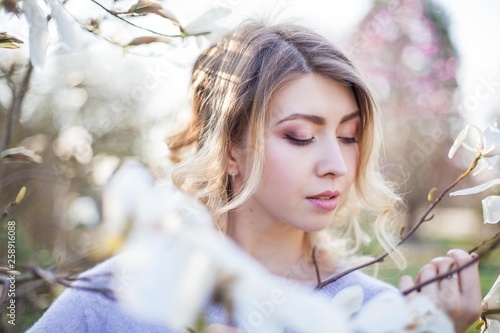 Portrait of a beautiful young woman near a magnolia. Spring.