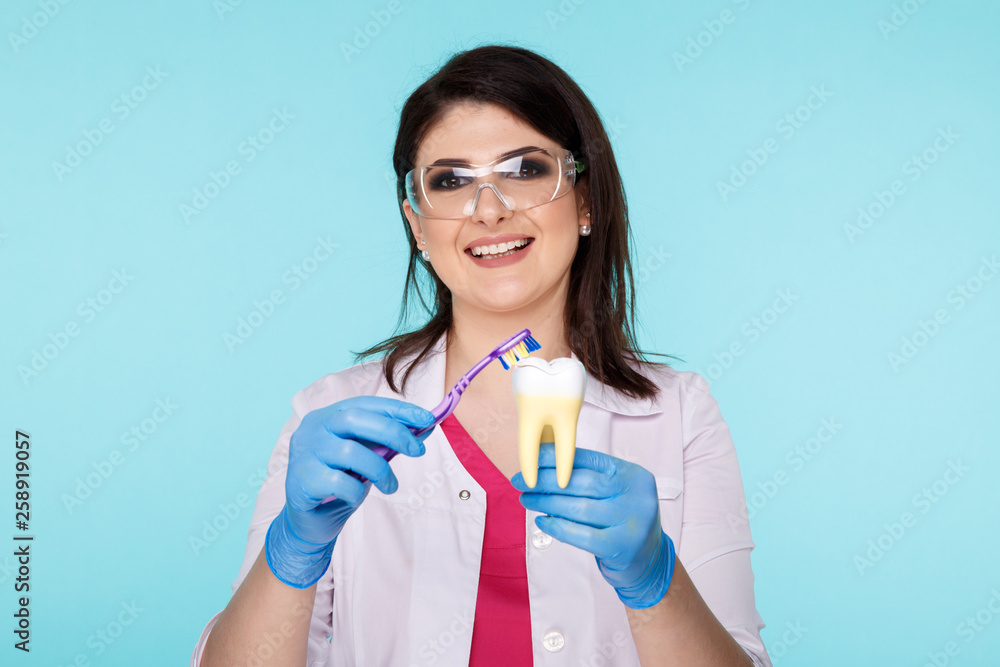 Female dentist with tooth model showing how to brush teeth Female dentist with tooth model showing how to brush teeth