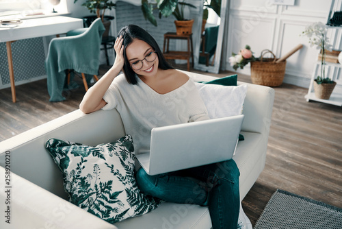 Time to relax. Top view of young woman using laptop while spending time at home