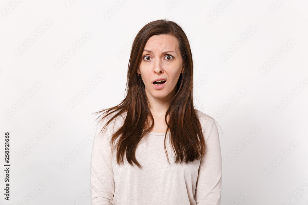 Portrait of perplexed bewildered puzzled young woman in light clothes standing and looking camera isolated on white background in studio. People sincere emotions lifestyle concept. Mock up copy space. Portrait of perplexed bewildered puzzled young woman in light clothes standing and looking camera isolated on white background in studio. People sincere emotions lifestyle concept. Mock up copy space.