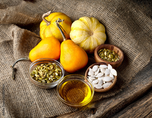 Pumpkin, pumpkin seeds and oil on wooden background