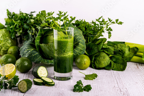 Detox green smoothie in glass at wooden white background.