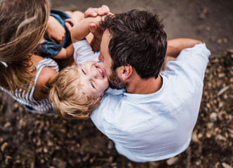 A young family with two toddler children outdoors by the river in summer, top view.
