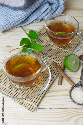 Hot lemon tea glasses with cinnamon stick on bamboo mat and craft.