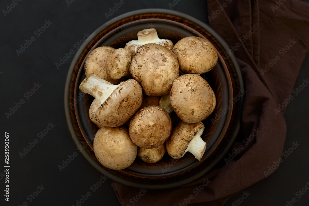 Brown champinon mushrooms (agaricus) in bowl on rustic wooden background. Healthy eating or vegetarian concept. Copy space. Top view Brown champinon mushrooms (agaricus) in bowl on rustic wooden background. Healthy eating or vegetarian concept. Copy space. Top view