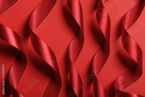 close up of wavy silk red ribbons on red background