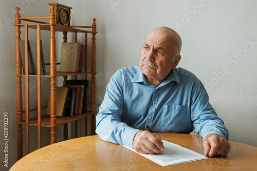 Old man writing notes or deciding to sign photo