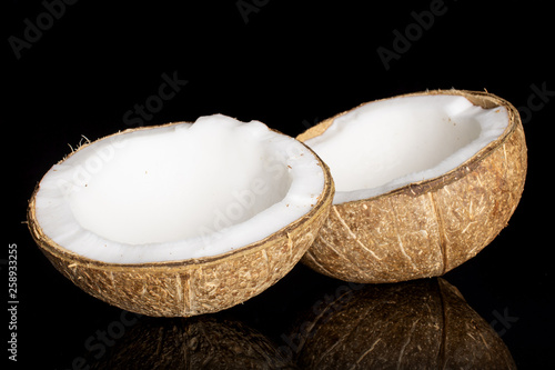 Group of two halves of fresh bio coconut isolated on black glass