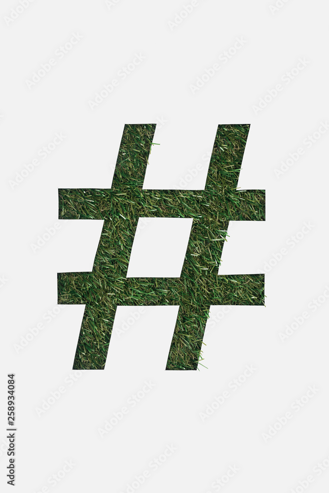 Obraz premium top view of cut out hashtag sign on green grass background isolated on white
