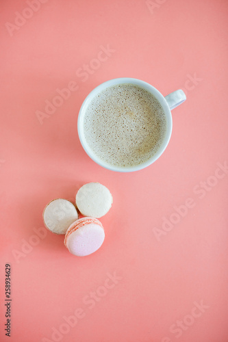 Cup of fresh coffee with macaron on living coral background