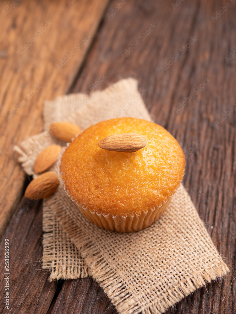 Close up a cup of almond cake against sack fabric on wooden table