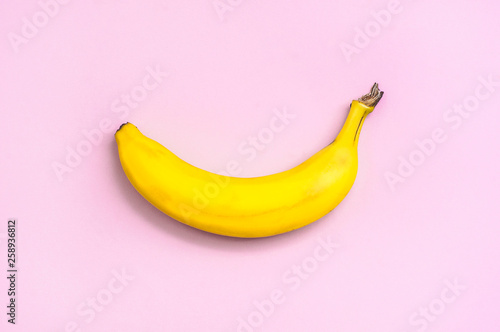 Bright yellow banana on a pink background. Top view