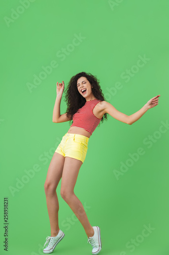 Full length photo of adorable woman having fun and dancing isolated over green background