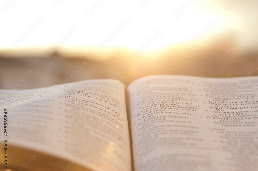 Open Bible with bright sunset in the background. Close-up. Horizontal shot. - obrazy, fototapety, plakaty 