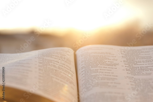 Obraz na plátně Open Bible with bright sunset in the background
