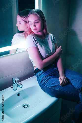 No drugs concept. Alone attractive woman looks away while sitting on white sink in night club's toilet. Healthy lifestyle and drug addition