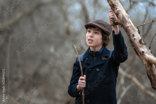 Portrait of a boy in a coat and cap against the background of nature.