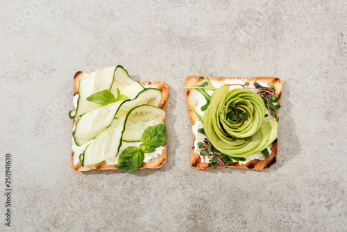 Top view of toasts with cut vegetables on textured surface