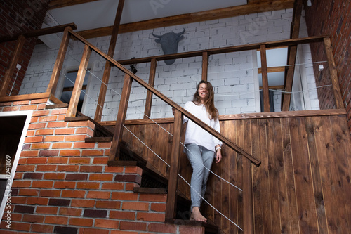 Young woman stands on the stairs and looks down in the living room