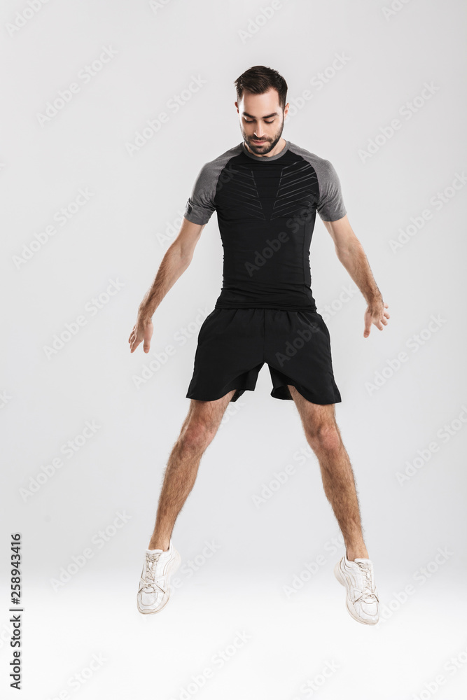 Fototapeta premium Handsome young sports fitness man posing isolate over white wall background jumping.