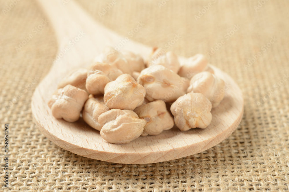 Garbanzos gordos en una cuchara de madera sobre fondo de tela, detalle Garbanzos gordos en una cuchara de madera sobre fondo de tela, detalle