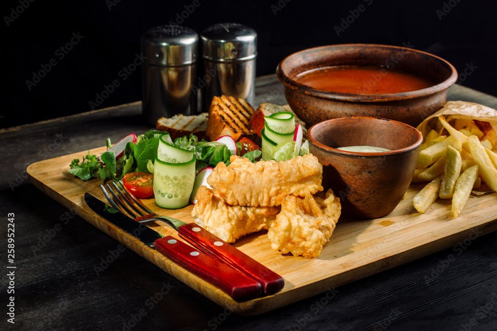 Lunch on a wooden board. Soup, chicken breast, salad and sauce. Lunch on a wooden board. Soup, chicken breast, salad and sauce.