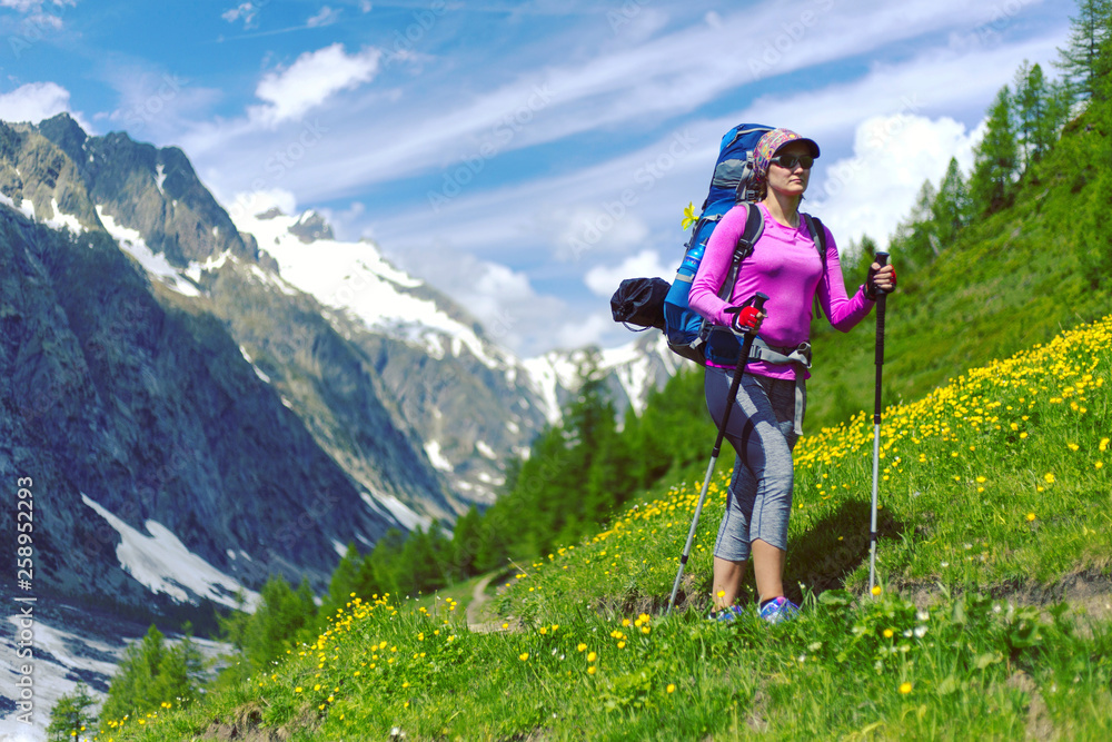 Woman hiking in mountain range. Rear view of a female backpacker walking on a small foot path in a mountain landscape. Image for trekking, hiking or climbing.