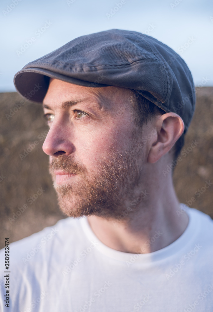 A young handsome man sitting alone and contemplating life by the quiet sea, surrounded by raw concrete sea defence wall. Mental health and depression road to recovery. A young handsome man sitting alone and contemplating life by the quiet sea, surrounded by raw concrete sea defence wall. Mental health and depression road to recovery.