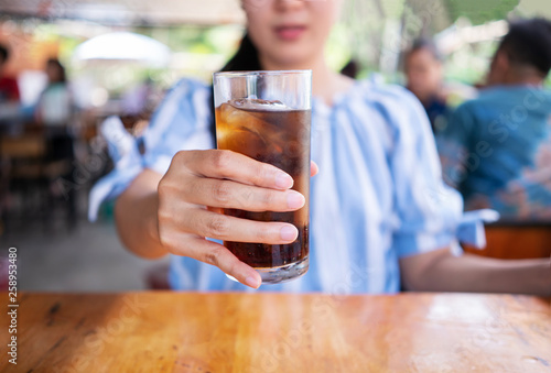 Woman hand giving glass of cola.